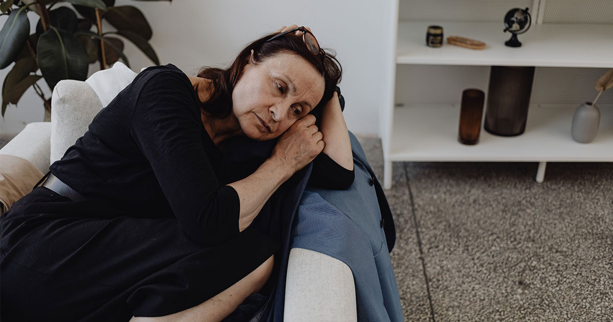 Femme épuisée par la charge mentale émotionnelle, assise sur son canapé